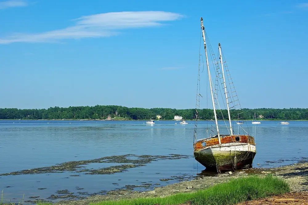Old sailboat resting on the tidal shore at Adams Point in Durham, New Hampshire