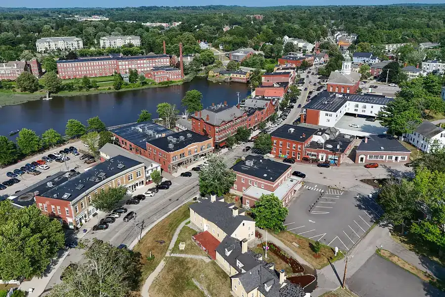 Aerial view of brick buildings and church steeples in downtown Exeter, New Hampshire, beside the river