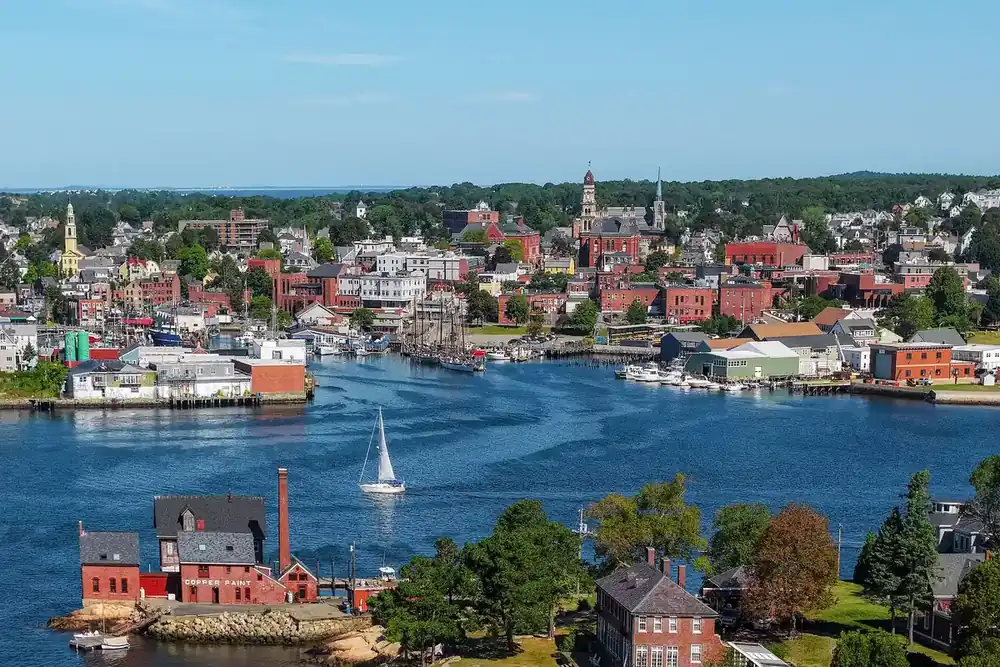 Aerial view of Gloucester Harbor with a sailboat and the city behind it in Massachusetts
