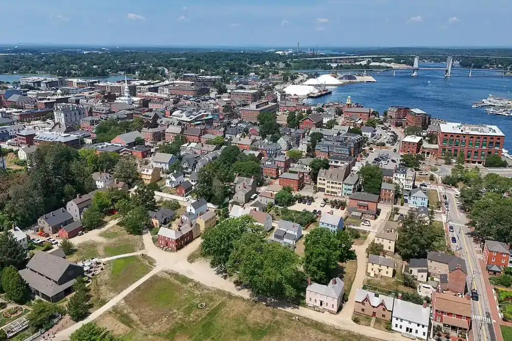 Aerial view of Portsmouth, New Hampshire, with older homes, downtown streets and the harbor beyond