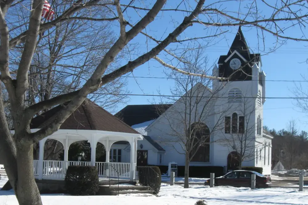 Town common gazebo and white church steeple in winter in Raymond, New Hampshire